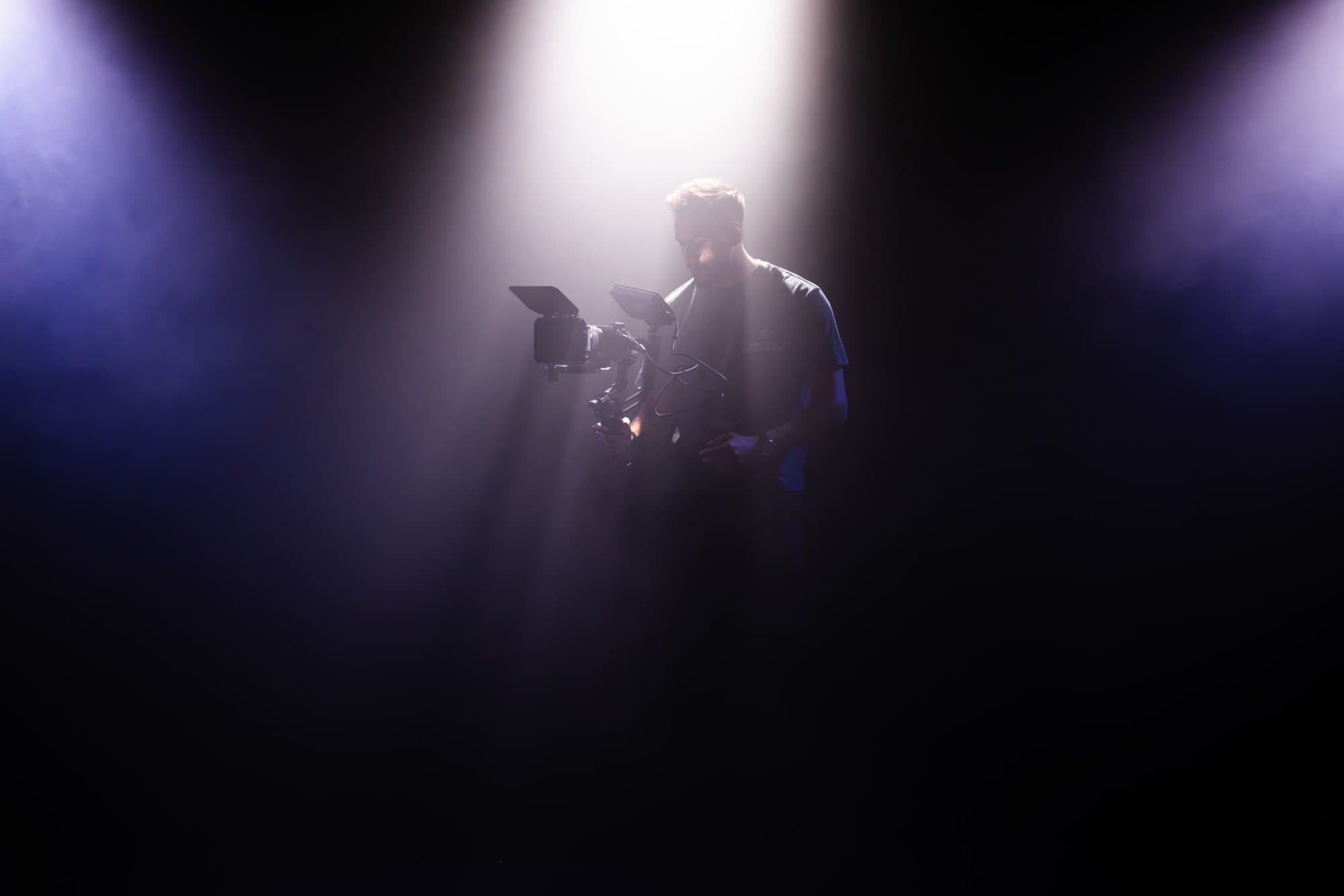 Rohan Nambiar filming with a gimbal-mounted camera under a beam of light